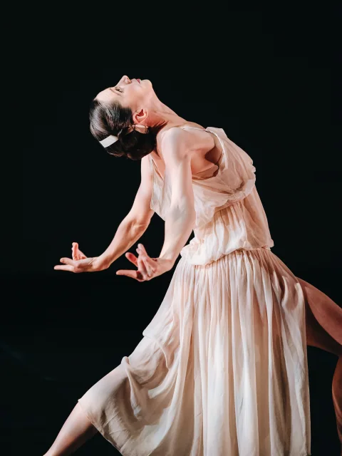Amy arching backwards with her arms open on stage